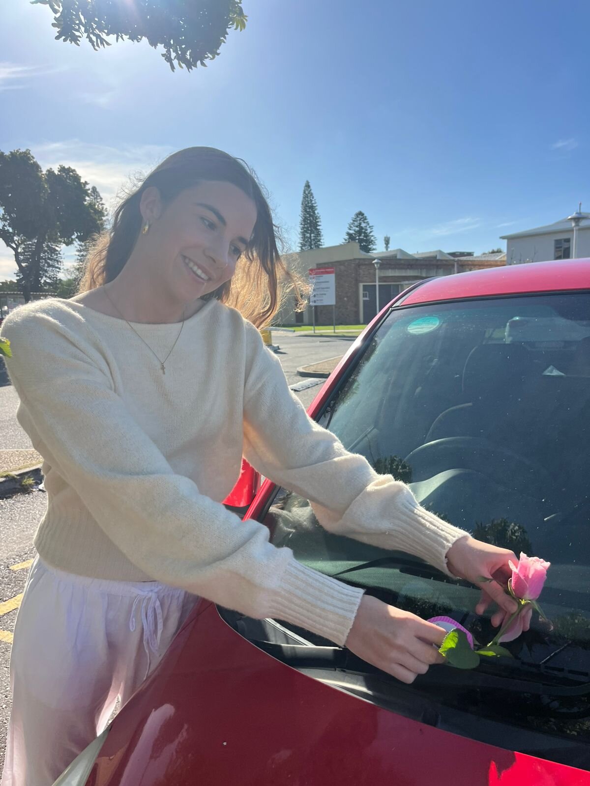 Leah leaving a flower and note on a car at the hospital