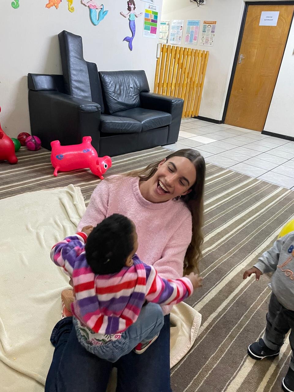 Leah laughing with a child at the home