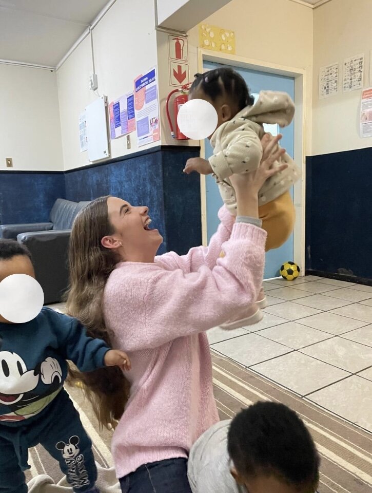 Leah, founder of Little by Little, laughing with a child at Christine Revell Children's Home