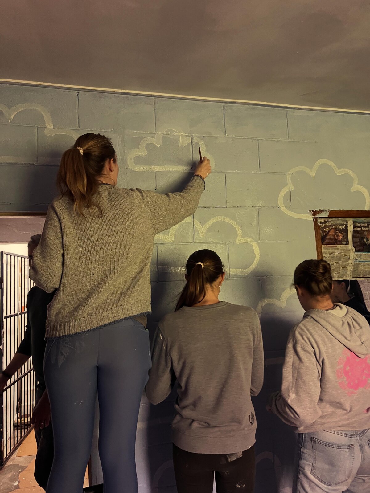 Volunteers painting a cloud mural at Kleenvrygeestes School
